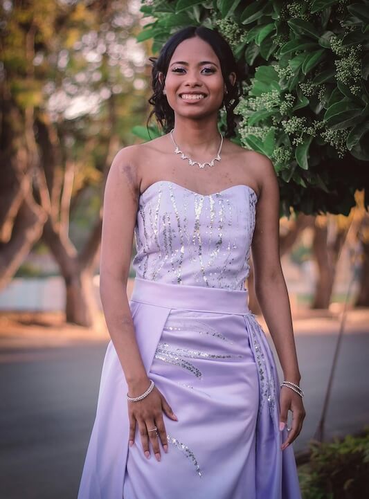 dress preservation Woman in a strapless lavender dress stands outdoors, smiling, with trees in the background.
