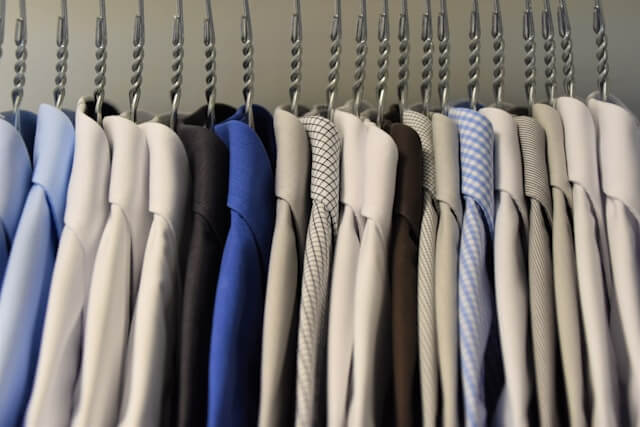 A row of neatly hung dress shirts in various colors and patterns on hangers.